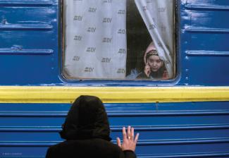 A father waves goodbye to his daughter as she leaves to seek refuge in Poland.