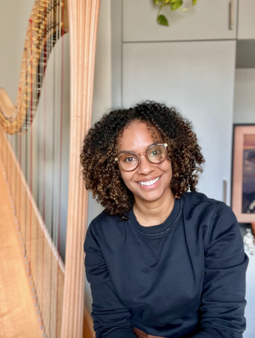 a woman smiling at the camera with harp in the background