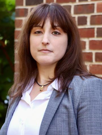 Woman in a gray blazer standing in front of a brick wall